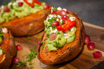 Healthy food - Baked sweet potatoes served with guacamole, feta cheese and pomegranate