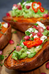 Healthy food - Baked sweet potatoes served with guacamole, feta cheese and pomegranate