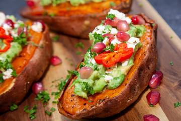 Healthy food - Baked sweet potatoes served with guacamole, feta cheese and pomegranate