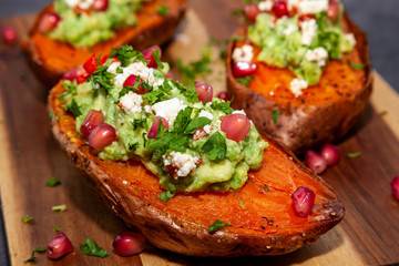 Healthy food - Baked sweet potatoes served with guacamole, feta cheese and pomegranate
