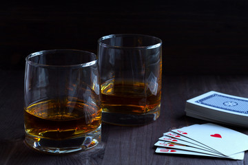 alcoholic drinks. glass of whiskey on a black background. two glasses of whiskey on a wooden background with a deck of cards. horizontal orientation
