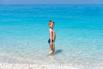 One boy is standing in the water on the beach