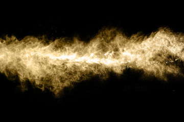 Golden powder explosion on black background. Freeze motion.