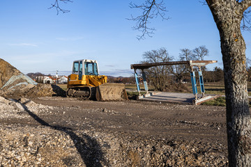 disused building site with bulldozer and a pile of dirt on a sunny day.