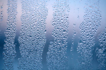 Drops of condensed steam, water drops. Close up detail of moisture condensation problems. Hot water vapor condensed on the cold window glass