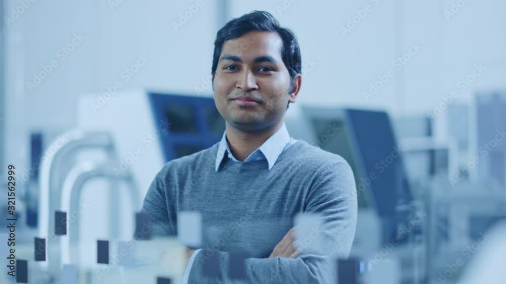 Poster modern factory office: portrait of handsome indian engineer crosses arms and smiles charmingly. in t