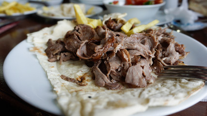 Turkish or Arabic traditional doner with pita bread / lavash on plate. Nutrition concept. Turkish, greek or middle eastern style doner kebab food on restaurant wooden table background.	