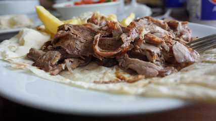 Turkish or Arabic traditional doner with pita bread / lavash on plate. Nutrition concept. Turkish, greek or middle eastern style doner kebab food on restaurant wooden table background.	