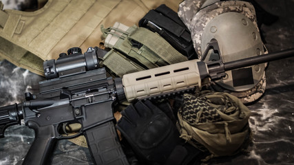 Close up of equipment carried by a Military Contractor featuring an AR15, ammunition, gloves, and body armor.