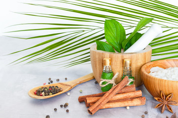 Closeup wooden bowl with salt, mortar pounder with herbs, small bottles with aromatic oils, healing spices are on table. Ayurveda salon concept. Preparation for relaxing spa treatments, massage.