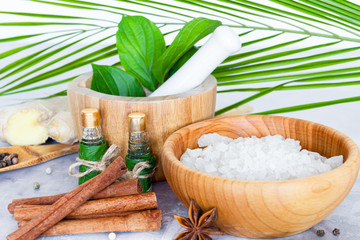 Obraz na płótnie Canvas Closeup wooden bowl with salt, mortar pounder with herbs, small bottles with aromatic oils, healing spices are on table. Ayurveda salon concept. Preparation for relaxing spa treatments, massage.