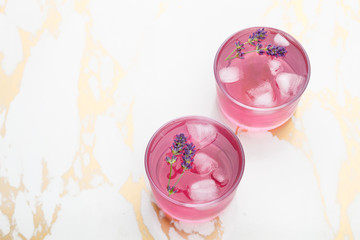 Lavender lemonade with ice on a golden marble background