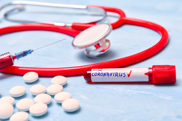 Positive virus Coronavirus blood test, pills, syringe and stethoscope on blue copy space background for a banner