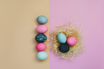 Line of Easter eggs and nestle with eggs on yellow and pink background