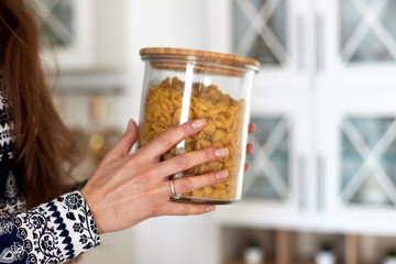 Female hand holding a glass jar with flakes