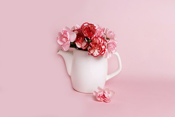 Kettle with colors on a pink background. Wishes of a good morning and a good day, minimal holiday concept. Postcard for Women's Day or Valentine's Day, birthday greetings, wedding, gift for loved ones
