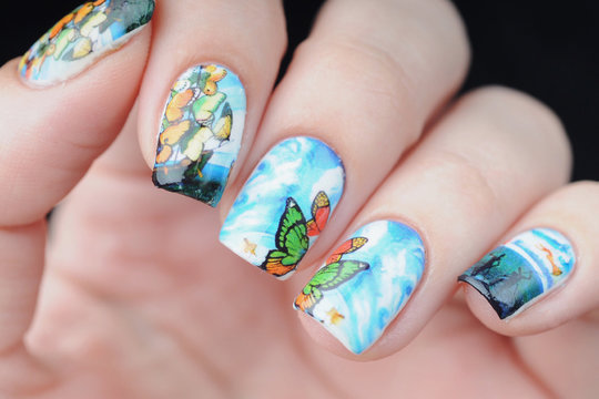 blue color manicure with butterfly pattern with clouds, ocean and ship