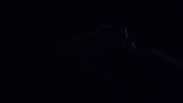 Male hand cocks the hammer of a .357 magnum handgun in darkness with flashes of light.  ECU in 4K.