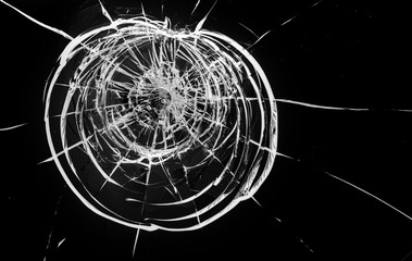 Round white cracks in glass on black background.