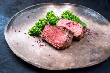 Barbecue dry aged wagyu roast beef natural sliced offered with rapini and salt as closeup on a...