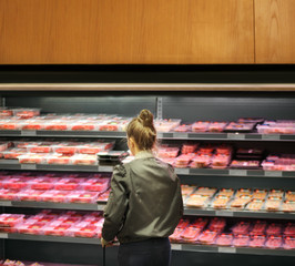 Woman purchasing a packet of meat at the supermarket	