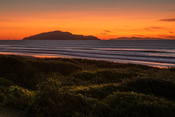 Kapiti Island sunset from Otaki Beach with long exposure to give blurred waves