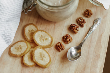 Sliced banana and peeled walnut on a wooden table. Yogurt in a glass bowl. Natural food.