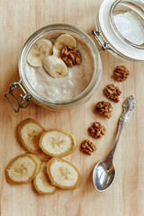 Yogurt in a glass bowl with sliced banana and walnut. Healthy food in the morning.