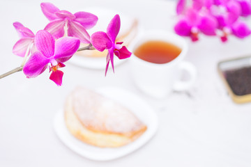 Cup of tee, flowers, homemade buns with cottage cheese on white wooden background. Love, spring mood concept.