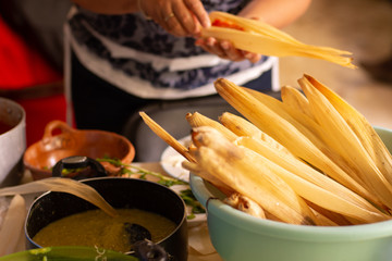 Woman cooking delicious mexican tamales at home kitchen