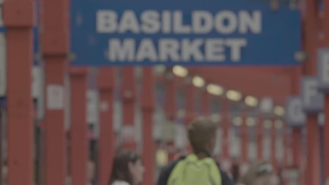 Upwards panning shot from people to the Basildon Market sign