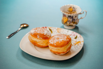 Cup with tea and donuts with icing sugar.