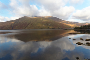 Mountain with reflection in fjord of Connemara, Ireland. Blue sky with white cloud, brown, gold and green landscape