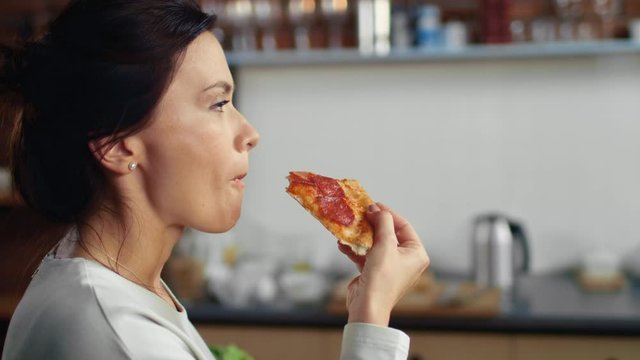 Woman biting slice of pizza at home. Hungry girl eating pizza from box.