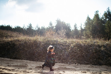 Cute little smiling girl running in autumn forest. Disobedience. happiness. Side view
