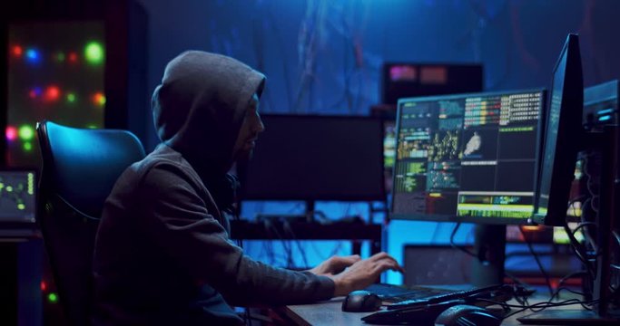 Young Caucasian man software developer working at night on two computers simultaneously and programming virus or antivirus.