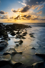 Fototapeta na wymiar Surf flowing over rocks at sunrise on Singer Island