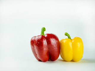 Red and yellow bell peppers with water droplets on a white background.