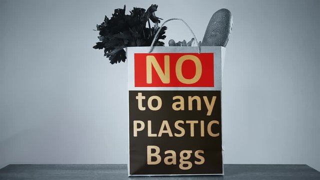 Placing paper bag with slogan no more plastic bags onto a table. Enviroment conncept
