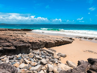 Australian beach with rocks in Noosa national park on sunny summer day with blue sky