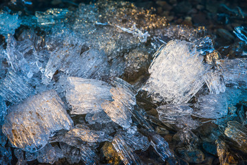 Pieces of melting ice under the bright Spring sun on the river bank. Selective focus macro shot with shallow DOF