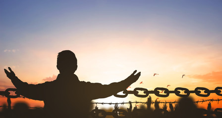 China Closed city concept: Silhouette refugee hands raising and barbed wire on sunset sky background