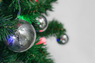 Silver bauble hanging from a decorated on Christmas tree, copy space.
