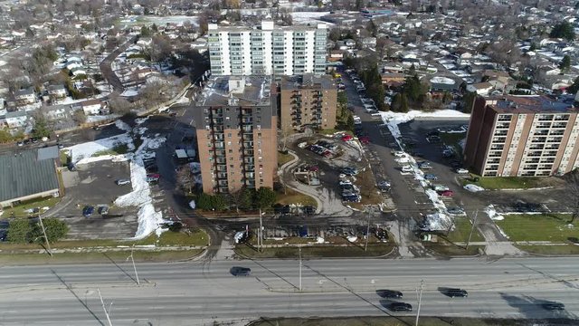 Short Bus And Regular Yellow School Bus Driving Down Road Past Each Other In Front Of Apartments Drone Shot