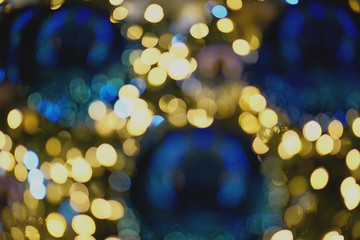 Blur bauble hanging from a decorated on Christmas tree, warm light bokeh.