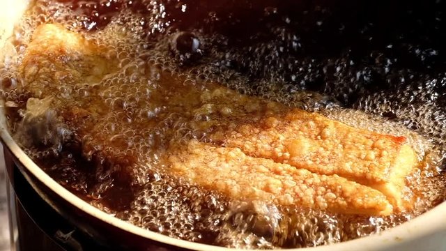 Deep frying crispy pork belly on hot oil in pan , traditional of thai food.