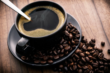 Hot black coffee and coffee beans on the wooden floor
