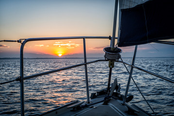 Sailing toward sunrise or sunset on sailboat on the ocean heading for shore in Texas