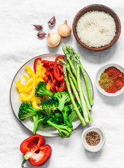 Ingredients for vegetarian paella - fresh vegetables sweet peppers, broccoli, asparagus, rice and spices on light background, top view