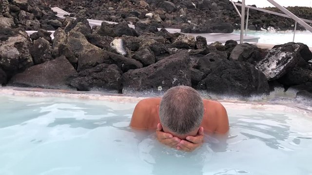Man wahing face in thermal water